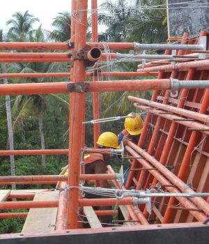 A construction worker is working on the scaffolding.