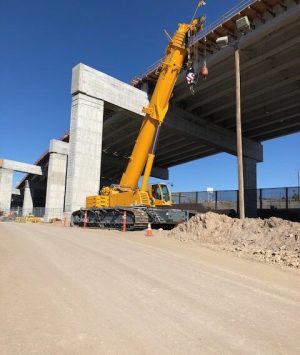 A large crane is on the ground near some concrete.