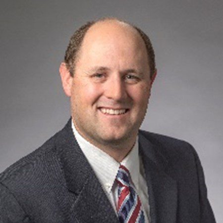 A man in a suit and tie smiling for the camera.