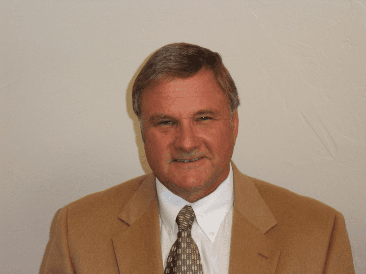 A man in a suit and tie smiling for the camera.