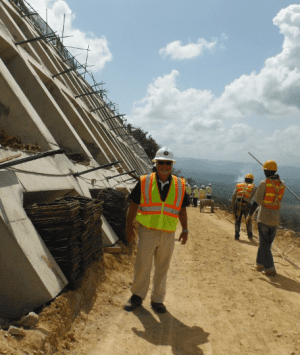 A man in safety gear standing on top of a hill.