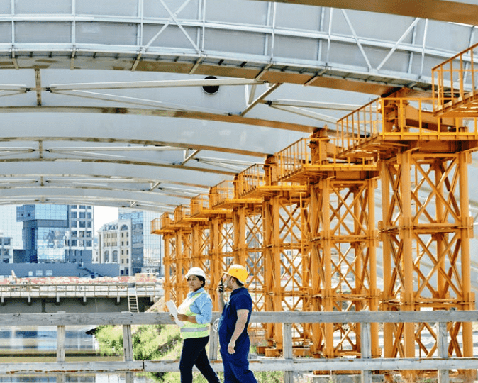 Two men walking on a bridge near a building.