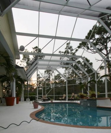 A pool with an open roof and a large glass ceiling.