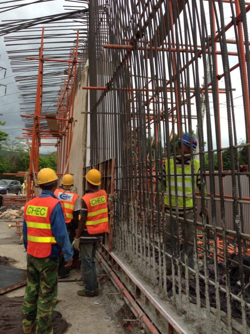 Construction workers inspect steel reinforcement on a building site.